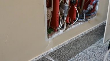 Bir telefon bağlantı kutusu açıldı: Ağ operatöründen bir teknisyen bir apartmanın veri ağına bağlanmak için boruya optik fiber yerleştiriyor.
