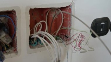 İşteki bir elektrikçi: beyaz fiber optik guania 'nın bağlandığı bir kabloyu elleriyle çekiyor. Önce bağlantı kutusundan çıkan yeşil kabloyu sonra da beyaz kabloyu görüyor.