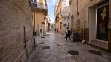 Lecce, Puglia, İtalya. Ağustos 2021. Pov görüntüleri tarihi merkezin sokaklarında yürüyor. Bir kişi önümüzde yürüyor. Yan sokağı gözetlemek için duruyoruz. Güzel bir yaz günü.