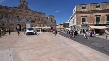 Ostuni, Puglia, İtalya. Ağustos 2021. Piazza Della Libert 'in Pov görüntüleri. Yürürken turist gruplarıyla karşılaşıyoruz, arka planda San Francesco kilisesi ve belediye binası..