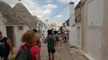 Alberobello, Puglia, İtalya. Ağustos 2021. Büyüleyici tarihi köyün inanılmaz görüntüsü. İnsanlar bu büyüleyici kasabayı ziyaret etmek için dar sokaklara akın ediyorlar. Güzel bir yaz günü.