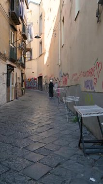 Napoli, İtalya, 29 Aralık 2024. Tarihi merkezde bir ara sokakta, sokağa asma kilit ve zincirle konmuş halatların tuhaflığı. Bir turist çevreye bakar. Seyahat yerleri.