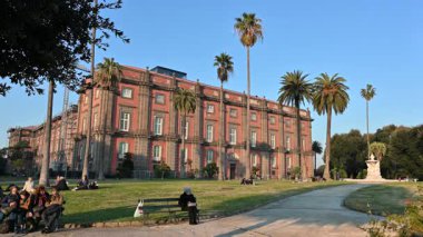 Napoli, İtalya, 30 Aralık 2024. Capodimonte Kraliyet Sarayı 'nın kısa maskaralığının görüntüleri. Sıcak öğleden sonra ışığı onu aydınlatıyor ve insanlar çimlerin üzerinde rahatlıyor. Yakınlaştır.