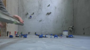 Banyo tadilatı devam ediyor; zemin fayanslarla döşendi. Mavi ve siyah uzay araçları hala yerinde. The tiler doğru yerleştirildiğinden emin olmak için karoları ruh seviyesiyle kontrol ediyor..