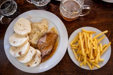 Prag, Czech Cumhuriyeti, 9 Ağustos 2023. Kızarmış domuz eti, lezzetli ekmek köfteleri, lahana turşusu ve yanında da bir barda servis edilen patates kızartmasının yer aldığı geleneksel Çek yemeği.