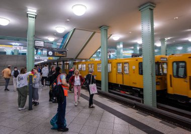 Berlin, Almanya, 10 Ağustos 2023. Alexander Platz metro istasyonunda vurulmuş. Parlak sarı bir tren geliyor. Platformda insanlar binmek için bekliyor..