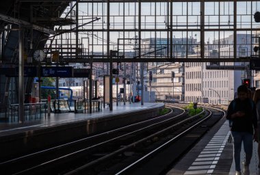 Berlin, Almanya, 11 Ağustos 2023. Friedrichstrabe platformlarında bekleyen insanlar, modern cam ve çelik kentsel istasyon mimarisinin altındaki mesafeye kadar uzanan çoklu raylar.