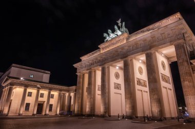 Berlin, Almanya, 13 Ağustos 2023. Berlin 'deki Brandenburg kapısı gece aydınlandı, neoklasik sütunlar ve karanlık gökyüzüne karşı kuadriga heykeli sergilendi.