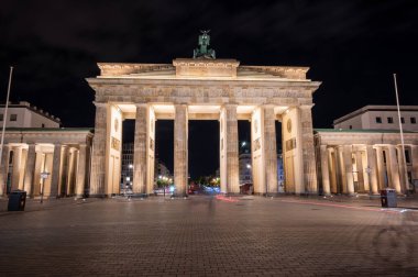 Berlin, Almanya, 13 Ağustos 2023. Berlin 'deki Brandenburg kapısı gece gökyüzüne karşı parlıyor, neoklasik anıt ve Alman birliği ve tarihinin sembolü, boş sokak