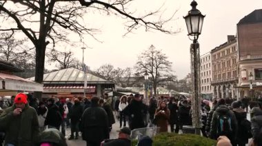 Münih, Almanya, 29 Aralık 2025. Avrupa 'nın tarihi bir şehir meydanında soğuk ve bulutlu bir kış gününde kalabalık bir açık hava pazarının keyfini çıkarıyor.