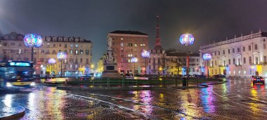Torino, İtalya 'da Piazza Carlo Alberto, anıtı, tarihi binaları, parıldayan dekoratif ışıkları ve bulanık araçları gösteriyor.
