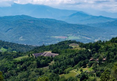 Piedmont kırsalında lavanta tarlaları, yemyeşil ormanları ve bulutlu gökyüzünün altındaki uzak dağları sunarak San Giovanni 'nin doğal güzelliğini ve tarımsal manzarasını gözler önüne seriyor.