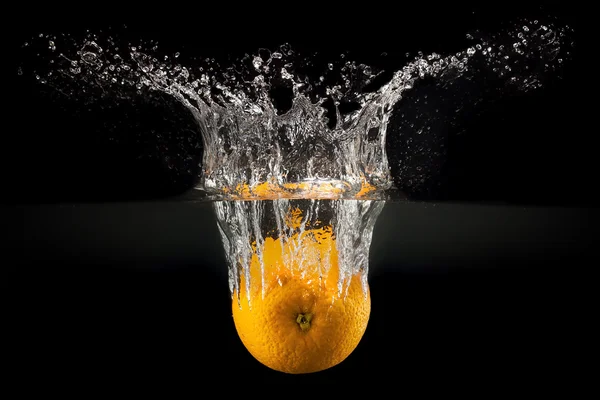 Frutas frescas que caen en el agua con salpicaduras sobre fondo negro —  Fotos de Stock