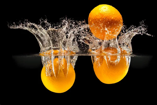 Grupo de frutas frescas que caen en el agua con salpicaduras sobre fondo negro — Foto de Stock