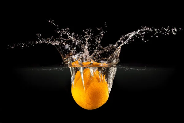 Frische Früchte fallen in Wasser mit Spritzer auf schwarzem Hintergrund — Stockfoto