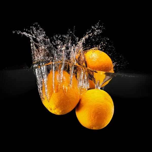 Group of fresh fruits falling in water with splash on black background — Stock Photo, Image