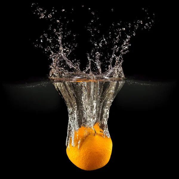 Frutas frescas que caen en el agua con salpicaduras sobre fondo negro —  Fotos de Stock