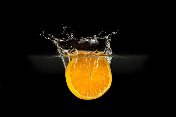 Fresh fruits falling in water with splash on black background — Stock Photo, Image