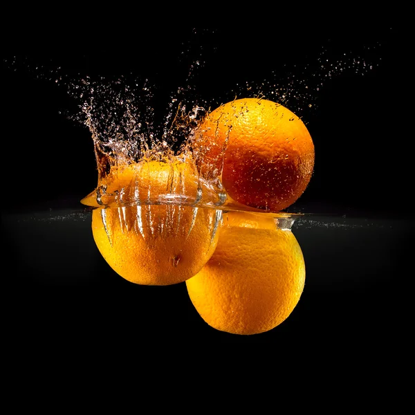 Group of fresh fruits falling in water with splash on black background — Stock Photo, Image