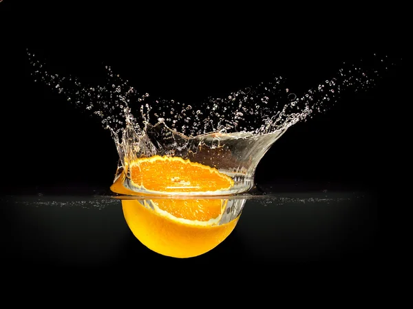 Fresh fruits falling in water with splash on black background — Stock Photo, Image