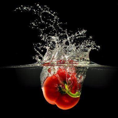 Kırmızı dolmalık biber su sıçrama ile siyah arka plan üzerine düşen