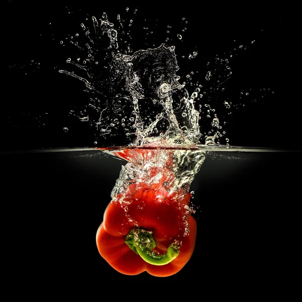 Peperoncino rosso che cade in acqua con spruzzata su fondo nero — Foto Stock