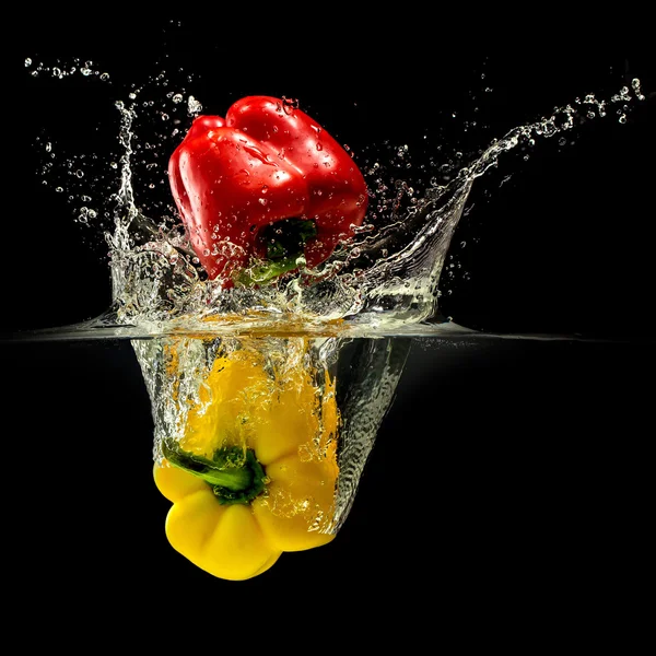 Group of bell pepper falling in water with splash on black background — Stock Photo, Image