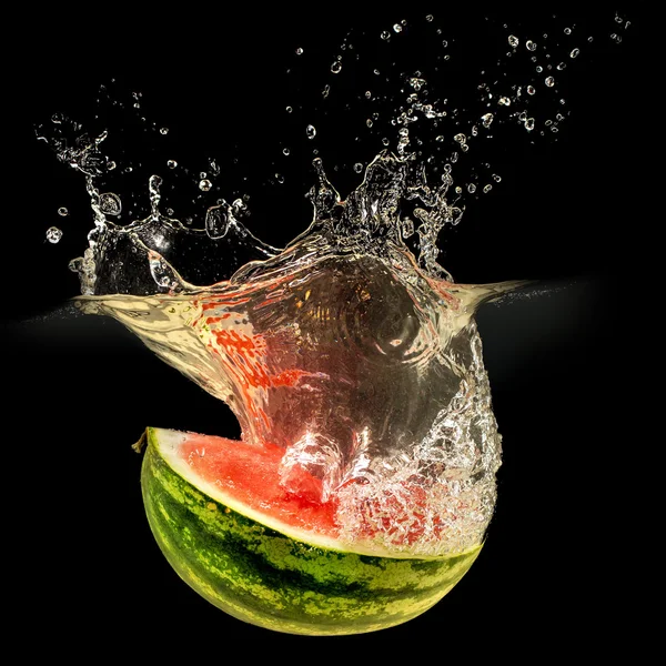 Frische Melone fällt in Wasser mit Spritzer auf schwarzem Hintergrund — Stockfoto