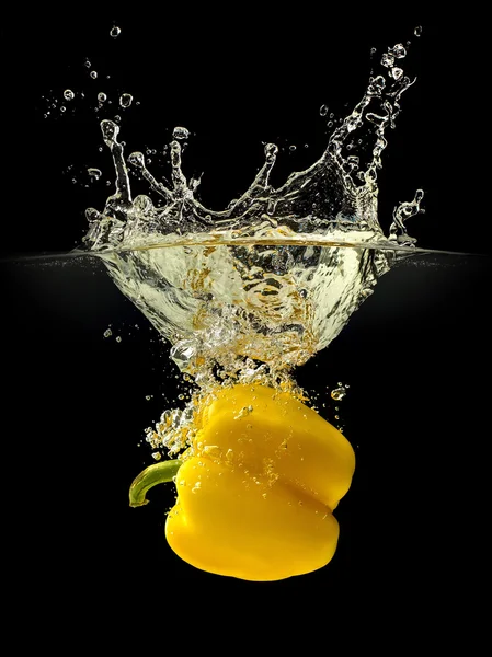 Gelbe Paprika fällt ins Wasser mit Spritzer auf schwarzem Hintergrund — Stockfoto