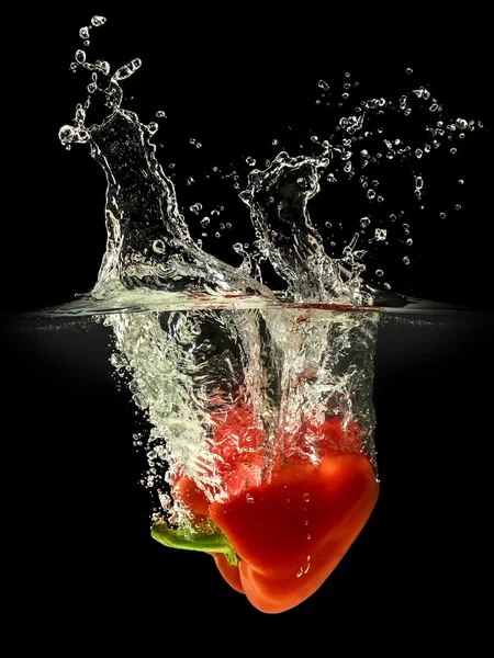 Red bell pepper falling in water with splash on black background — Stock Photo, Image