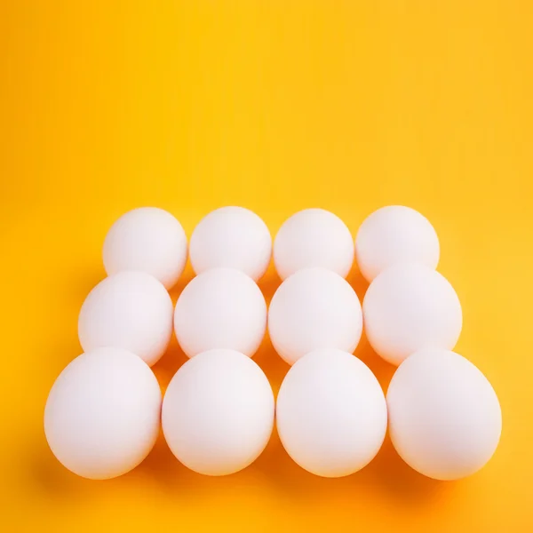 Ovos brancos sobre um fundo amarelo — Fotografia de Stock