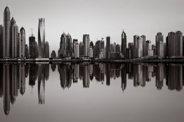 Tek renkli şehir gökdelenleri bulutlu bir gökyüzü altında sakin suyu yansıtan gökdelenler, kentsel gelişim konsepti, Dubai Marina Körfezi BAE