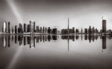 Tek renkli şehir gökdelenleri bulutlu bir gökyüzü altında sakin suyu yansıtan gökdelenler, kentsel gelişim konsepti, Dubai Marina Körfezi BAE