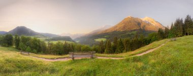 Berchtesgaden Ulusal Parkı, Yukarı Bavyera Alpleri, Almanya, Avrupa 'da gün batımında Hintersee Gölü yakınlarında yol ve bank ile Meadow. Gökyüzü yolu kırpılıyor