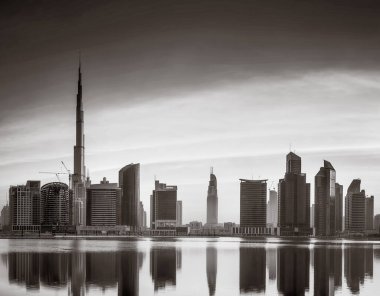 Tek renkli şehir gökdelenleri bulutlu bir gökyüzü altında sakin suyu yansıtan gökdelenler, kentsel gelişim konsepti, Dubai Marina Körfezi BAE