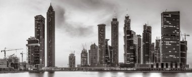 Tek renkli şehir gökdelenleri bulutlu bir gökyüzü altında sakin suyu yansıtan gökdelenler, kentsel gelişim konsepti, Dubai Marina Körfezi BAE