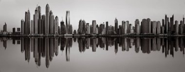 Tek renkli şehir gökdelenleri bulutlu bir gökyüzü altında sakin suyu yansıtan gökdelenler, kentsel gelişim konsepti, Dubai Marina Körfezi BAE