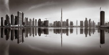 Tek renkli şehir gökdelenleri bulutlu bir gökyüzü altında sakin suyu yansıtan gökdelenler, kentsel gelişim konsepti, Dubai Marina Körfezi BAE