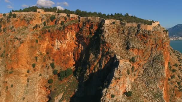 岩の多い牡牛座山脈のAlanya Fortressの壁の上の航空機のコッパーフライトは濃い緑の森で覆われ、地中海に圧倒されました。トルコのアンタルヤ県. — ストック動画
