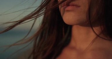 Huzurlu günbatımının tadını çıkaran güzel bir kadının portresi. Rüzgâr saçlara esiyor. 4K atış.