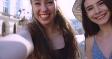 İki çekici mutlu kız sohbet ediyor ve şehirde selfie çekiyor..