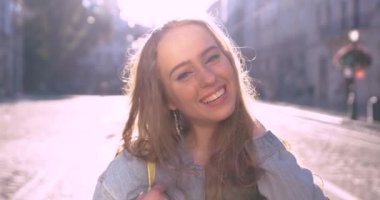 Uzun sarı saçlı çekici kız kameraya bakar ve gülümser..