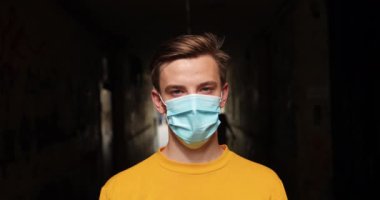 Tıbbi maske takan yakışıklı ve sokakta izole edilmiş sarı gömlekli hasta bir genç. Hastalık kavramı. Avrupalılar.