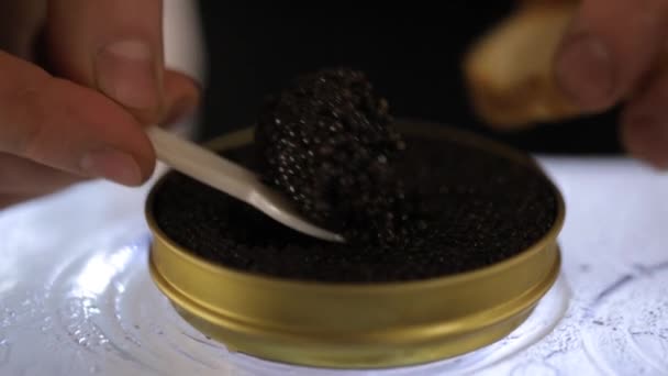 Close up hand picks a spoonful of black caviar. black caviar on the spoon. — Stock Video