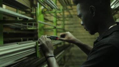 Çekici Afrikalı adam depo işçisi Caliper bir depodaki ürünlerin kalınlığını ölçer.
