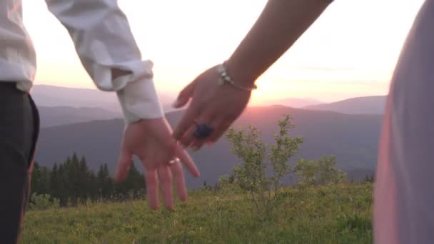 Egy pár kezet nyújt egymásnak. Közelkép a párról, amint fogják egymás kezét a naplementében. Romantikus kültéri kilátás. — Stock videók