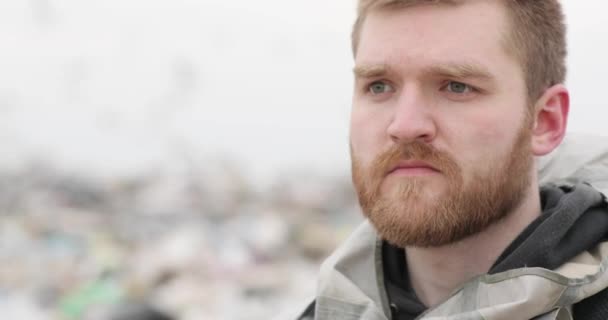 Close-up portret van een wrede man met baard met droevige ogen staat op stortplaatsen — Stockvideo