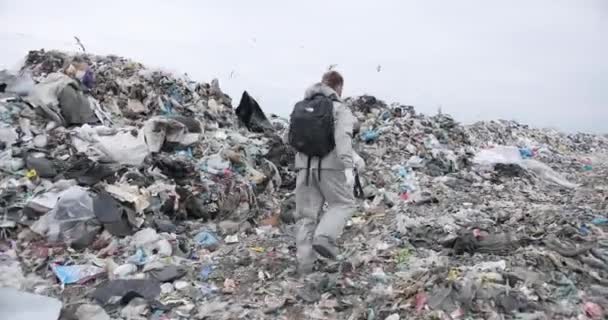 一个穿着特殊衣服、背着黑色背包的男人沿着垃圾堆跑着 — 图库视频影像