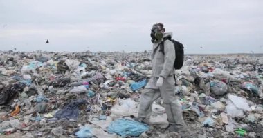 Sembolik çekim çevresel koruma, gaz maskeli bir adam çöp yığınını izliyor. çöp, atık, çöp, çöp, çöp, kirlilik, soyut çekim kıyamet, orta çekim