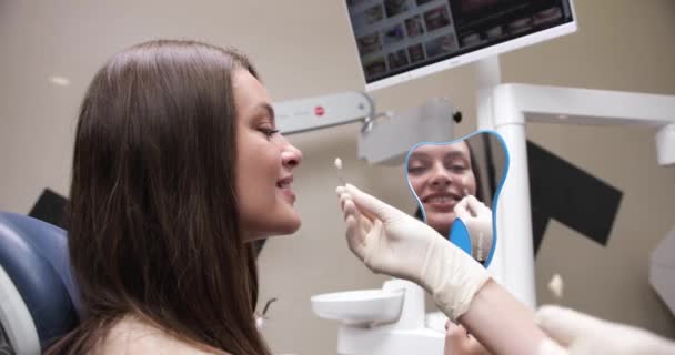 Lächelnde Patientin beim Zahnarzt. Stomatologe Wahl der Zahnfarbe einer hübschen Frau in der Klinik. Zahnweiß-Diagramm — Stockvideo